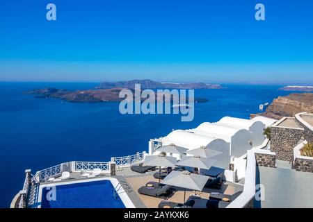 Greece. Santorini. Thira island. Hotel on the high bank in Oia. Pool and sun loungers for relaxation in sunny weather. Seascape Stock Photo