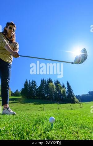 Femal golf player hitting a ball with driver Stock Photo