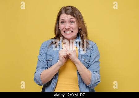 Awkward caucasian woman feeling embarrassed, confused nervous before exam isolated on yellow studio background. Omg I made a terrible mistake. Stock Photo
