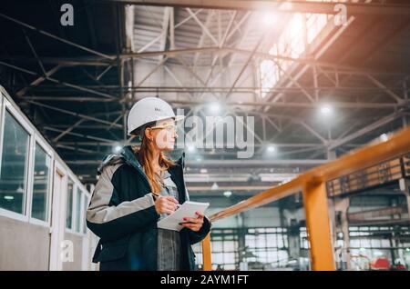 Production workshop. Young female engineer working in modern factory Stock Photo