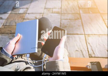 woman hands holding black smartphone charging battery from external power bank Stock Photo