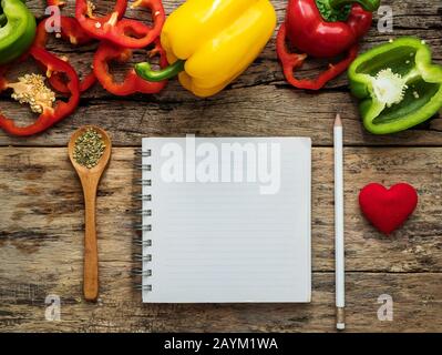 flat lay of blank recipe cooking book and utensils with herbs and colorful bell pepper over wooden background. top view with copy space. food recipe a Stock Photo