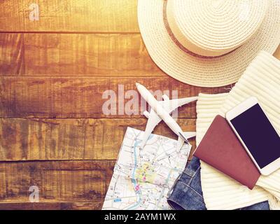 flat lay of passport , white plane model , map and traveler's accessories items on wooden background with copy space. travel and vacation concept Stock Photo