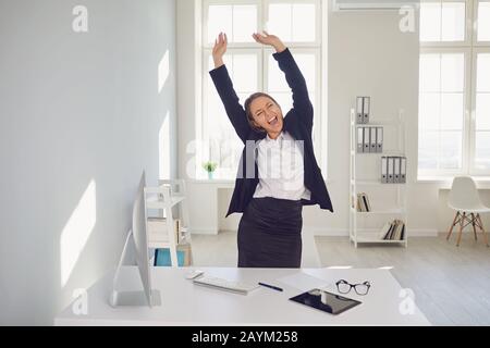 Excited happy businesswoman celebrating success at workplace Stock Photo
