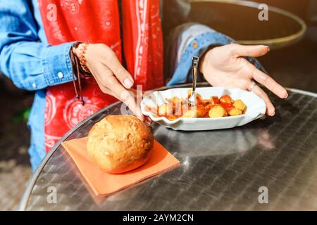 Woman Eating Currywurst with bread in Berlin street food cafe. Local german cuisine concept Stock Photo