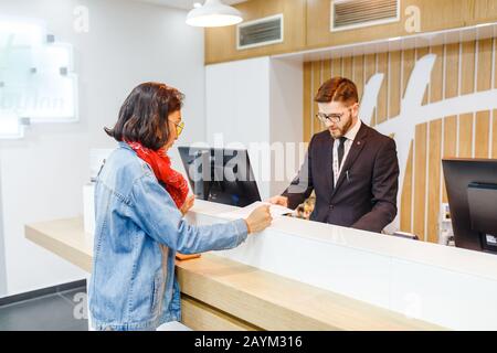18 MAY 2018, BERLIN, GERMANY: Hostess of HolidayInn hotel and guest communicate with each other at check-in reception Stock Photo
