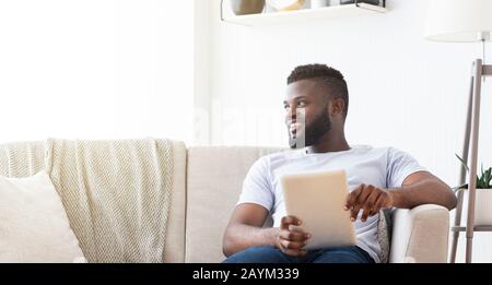 Cheerful african man resting at home with digital tablet Stock Photo