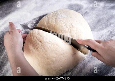 Cutting dough with knife on small portion for pizza dough. Stock Photo