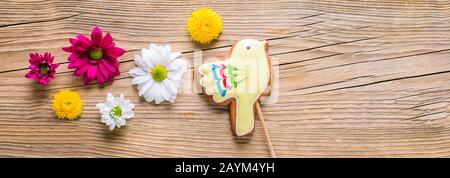 Easter gingerbread in the shape of a yellow bird on a wooden background, long banner Stock Photo