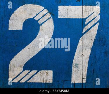 27. Weathered Old Painted Number On A Blue Wooden Surface. Stock Photo
