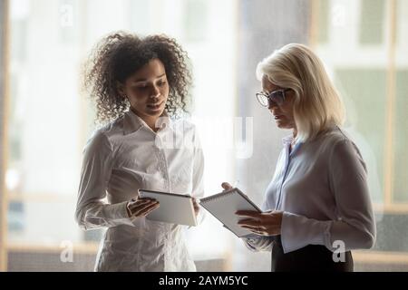 Diverse female colleagues talking making last preparations before start negotiations Stock Photo