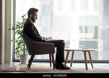 Arab businessman sitting in office lobby working on laptop Stock Photo