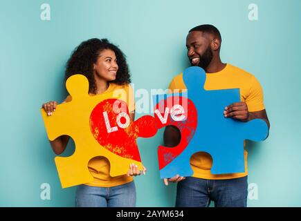 Couple with puzzles in hand over light blue background. Concept of integration, union, relationship and partnership Stock Photo