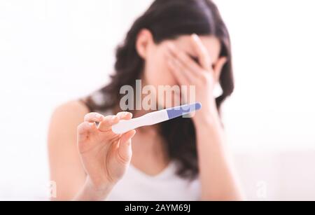 Desperate young woman showing result of pregnancy test Stock Photo