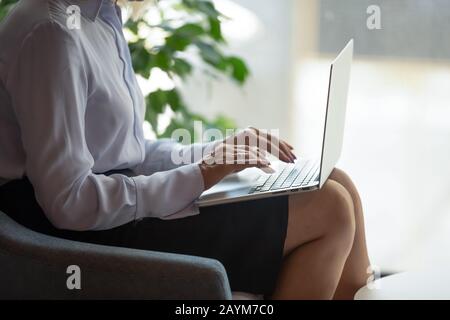 Closeup view businesswoman put computer on lap typing e-mail Stock Photo