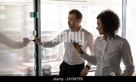 African and caucasian entrepreneurs writing on white board presentation Stock Photo