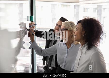 Three diverse entrepreneurs working on business strategy using white board Stock Photo
