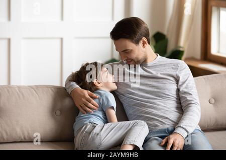 Happy young father embracing little kid son, communicating at home. Stock Photo