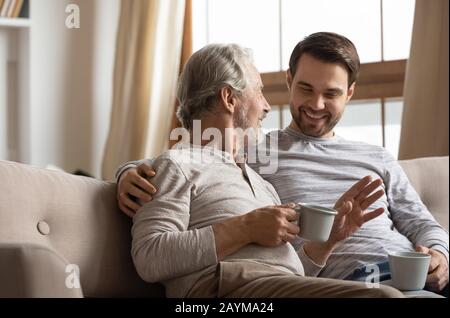 Joyful two generations family sharing news with cup of tea. Stock Photo