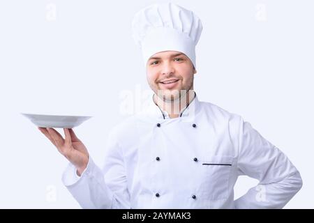 Chef Holding Empty Plate Posing In Studio On White Background Stock Photo