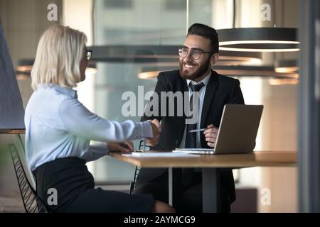 Middle eastern ethnicity HR manager hiring elderly woman people handshaking Stock Photo