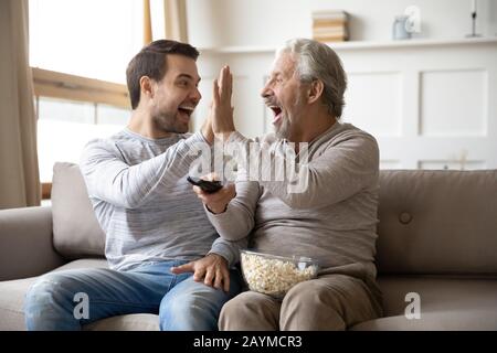 Happy young man giving high five to overjoyed father. Stock Photo