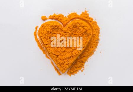 Heap ground turmeric isolated in heart shape on white Stock Photo