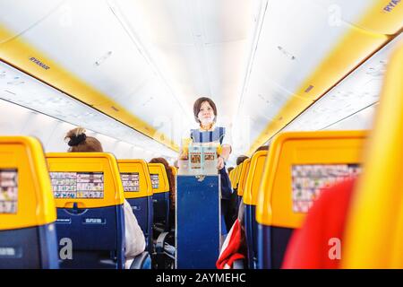 16 MAY 2018, BUDAPEST HUNGARY: Interior of Ryaniar airplane with passengers on seats and stewardess in uniform walking the aisle Stock Photo