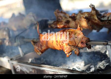 Pig roasting on stick. Street food concept Stock Photo