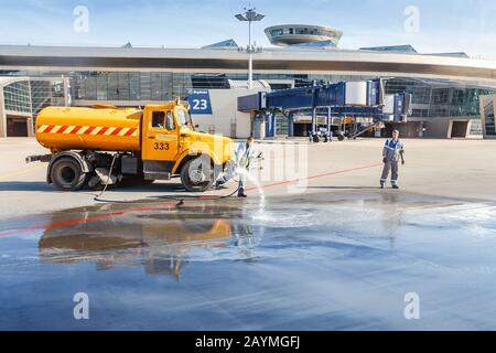 11 MAY 2018, MOSCOW, RUSSIA, VNUKOVO AIRPORT: Airfield service workers cleaning the airport apron truck Stock Photo