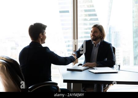 Bearded businessman in suit shaking hands with job seeker. Stock Photo