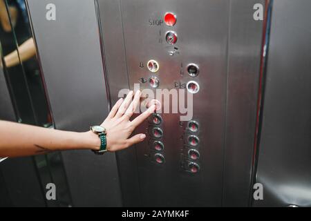 Woman hamd in the elevator or lift is pressing the button to get into the right floor Stock Photo