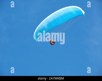 A man flies in his paraglider in front of blue sky Stock Photo