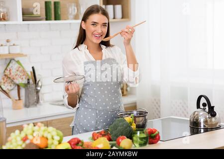Cooking concept. Woman tasting soup from spoon Stock Photo