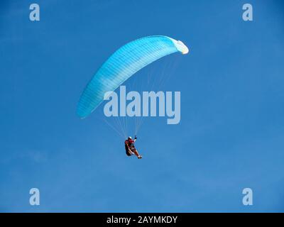 A man flies in his paraglider in front of blue sky Stock Photo