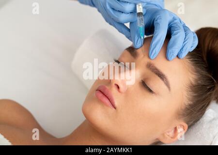 Beauty procedures. Woman receiving injection in forehead Stock Photo