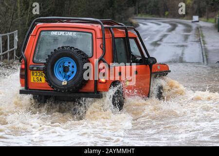 Majors Green, Birmingham, UK. 16th February, 2020. A driver of a converted Landrover Discovery makes his way through a flooded Peterbrook Road in Majors Green, Birmingham as the river burst its banks due to heavy rainfall from Storm Dennis, closing the road to all but specialist vehicles. Pic taken 16/02/2020. Credit: Stop Press Media/Alamy Live News Stock Photo