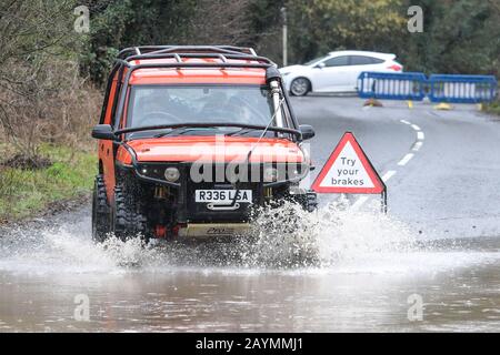 Majors Green, Birmingham, UK. 16th February, 2020. A driver of a converted Landrover Discovery makes his way through a flooded Peterbrook Road in Majors Green, Birmingham as the river burst its banks due to heavy rainfall from Storm Dennis, closing the road to all but specialist vehicles. Pic taken 16/02/2020. Credit: Stop Press Media/Alamy Live News Stock Photo