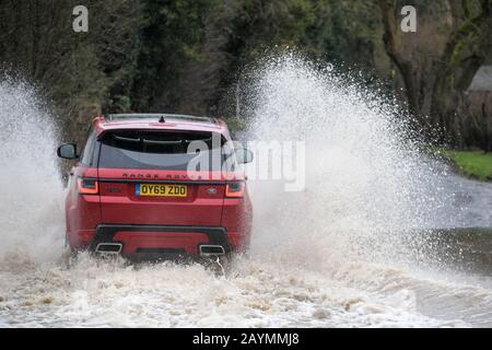 Majors Green, Birmingham, UK. 16th Feb, 2020. A Range Rover makes its way through a flooded Peterbrook Road in Majors Green, Birmingham as the river burst its banks due to heavy rainfall from Storm Dennis, closing the road to all but specialist vehicles. Pic taken 16/02/2020. Credit: Stop Press Media/Alamy Live News Stock Photo