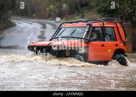 Majors Green, Birmingham, UK. 16th February, 2020. A driver of a converted Landrover Discovery makes his way through a flooded Peterbrook Road in Majors Green, Birmingham as the river burst its banks due to heavy rainfall from Storm Dennis, closing the road to all but specialist vehicles. Pic taken 16/02/2020. Credit: Stop Press Media/Alamy Live News Stock Photo