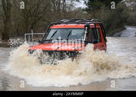 Majors Green, Birmingham, UK. 16th February, 2020. A driver of a converted Landrover Discovery makes his way through a flooded Peterbrook Road in Majors Green, Birmingham as the river burst its banks due to heavy rainfall from Storm Dennis, closing the road to all but specialist vehicles. Pic taken 16/02/2020. Credit: Stop Press Media/Alamy Live News Stock Photo