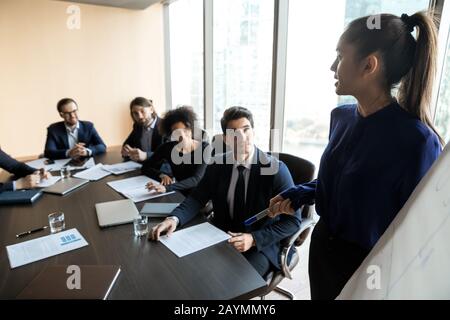Confident businesswoman lead flip charts presentation new project in boardroom. Stock Photo
