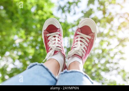 A foot in a sneakers shoes on a prk tree background, The concept of fashion and legs free from varicose Stock Photo