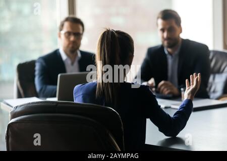 Hiring attractive woman applicant back sitting in front two HR. Stock Photo