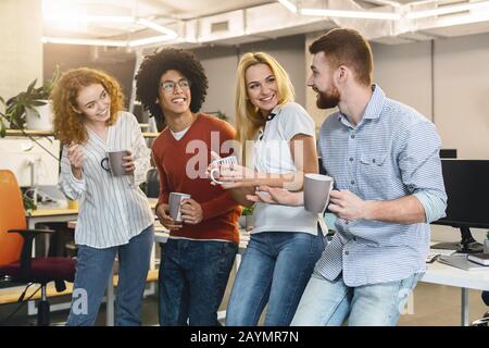 Business team drinking coffee while having free time in office Stock Photo