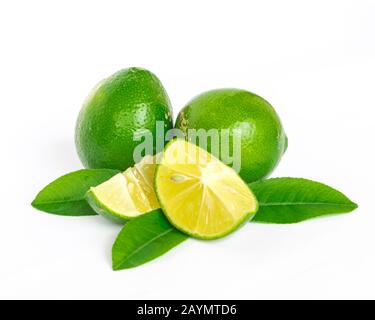 Pile of homegrown Asian limes with half cuts slices and green leaves isolated on white Stock Photo