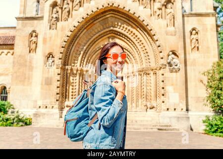 Traveller happy woman in front of The entrance to the Chapel of Jak in Vajdahunyad Castle in Budapest, Hungary. Stock Photo