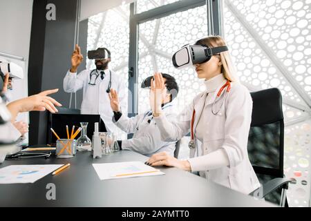 science, future technology, medicine and chemistry concept - young multiracial doctors or scientists in white lab coats and vr glasses working with Stock Photo