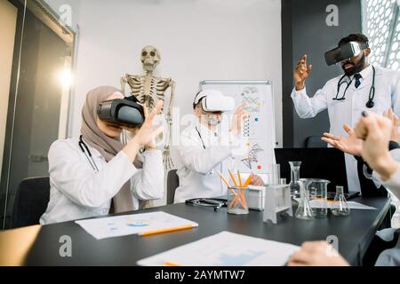 Group of multiethnic doctors scientists, African and Caucasian men, Muslim woman, wearing vr glasses working with 3d virtual content at modern Stock Photo