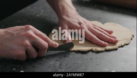 man cutting flat dough with knife, wide photo Stock Photo